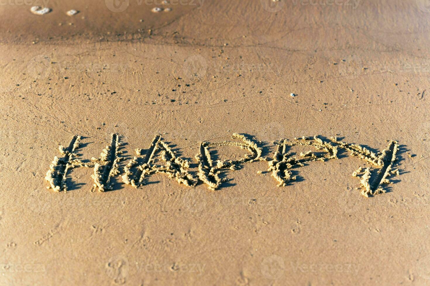 the inscription HAPPINESS on the sand of the beach photo