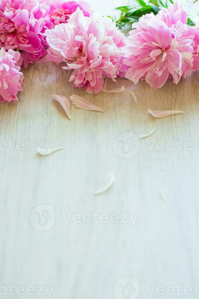 several branches of blooming pink peonies on a wooden table photo