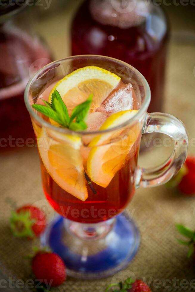 refreshing cool strawberry lemonade with lemon, ice and mint in a glass photo