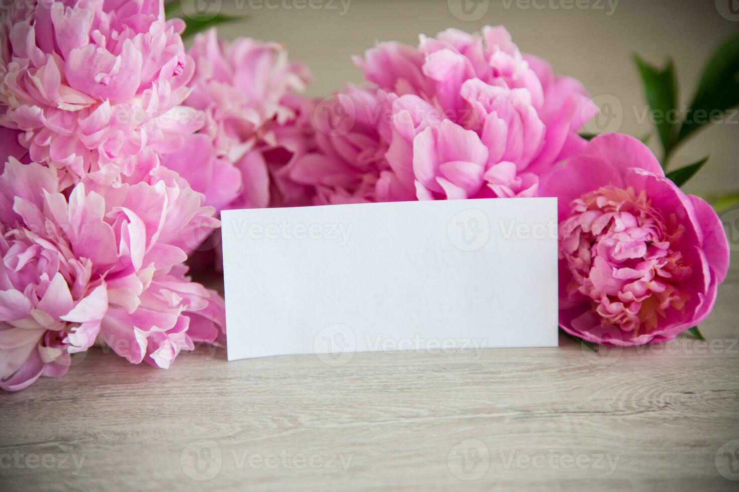 several branches of blooming pink peonies on a wooden table photo