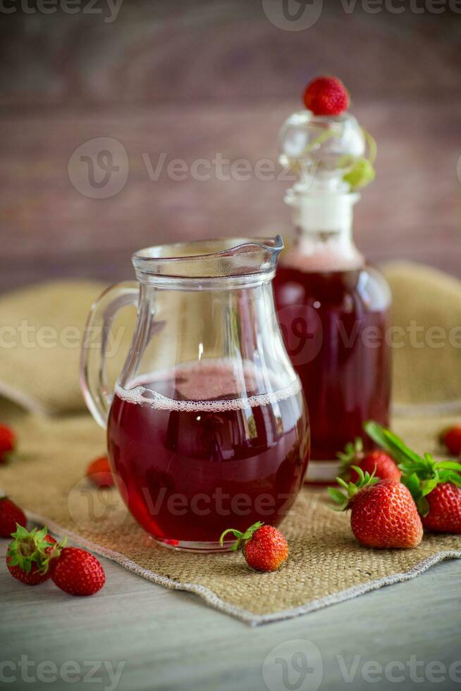 sweet cooked strawberry syrup in a glass decanter photo