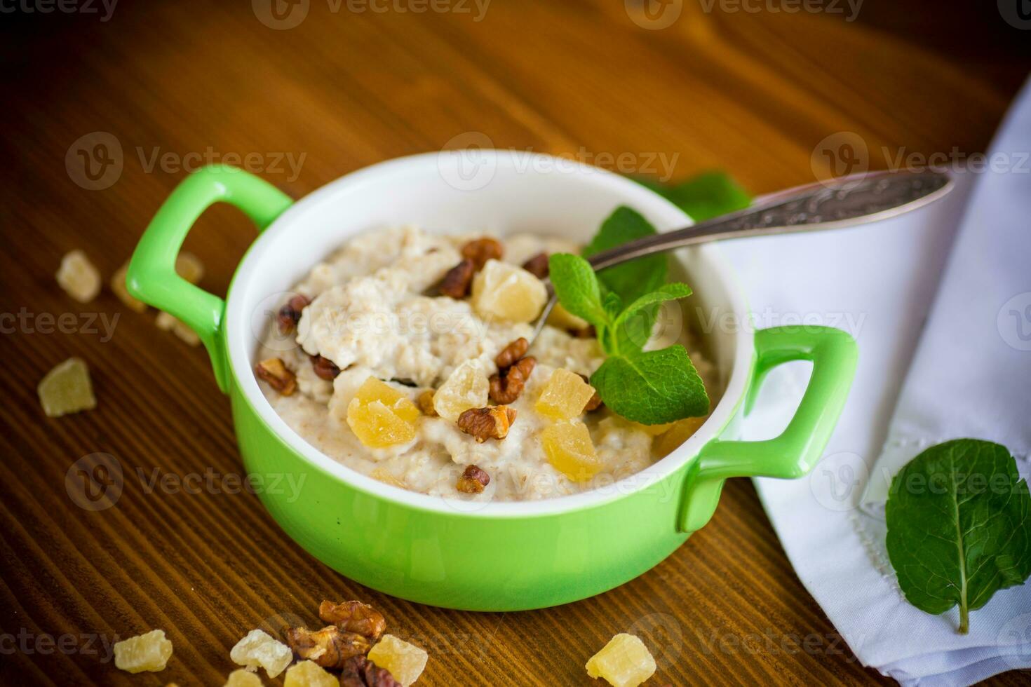 cooked boiled sweet oatmeal with nuts and candied fruits in a bowl photo