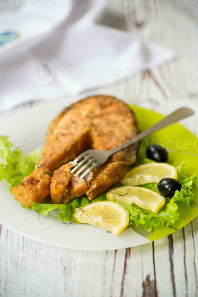 pedazo de frito salmón pescado en un plato con limón foto