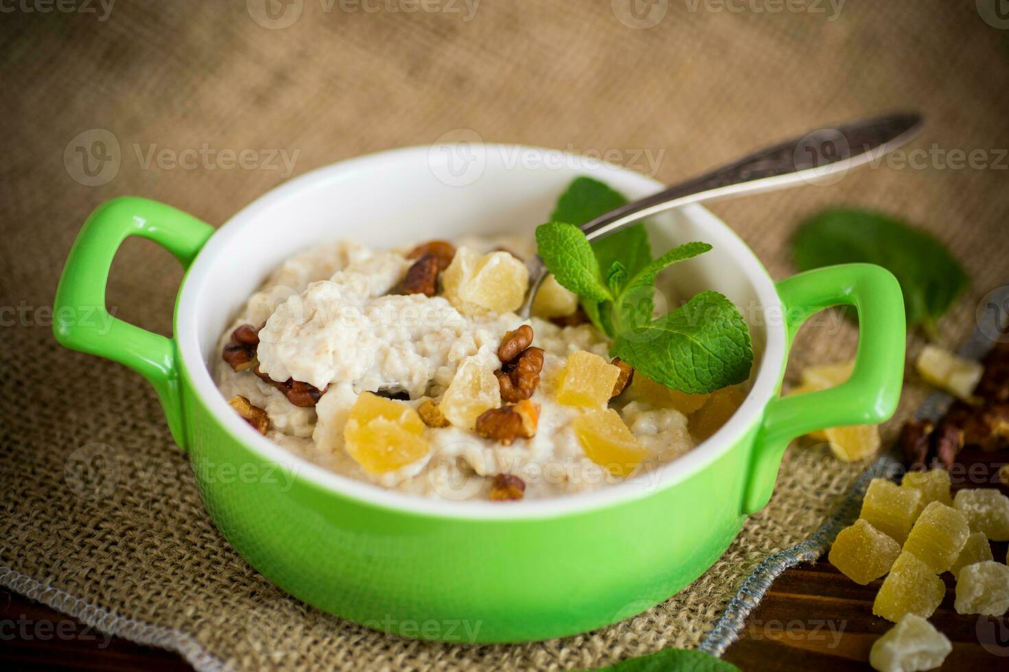 cooked boiled sweet oatmeal with nuts and candied fruits in a bowl photo
