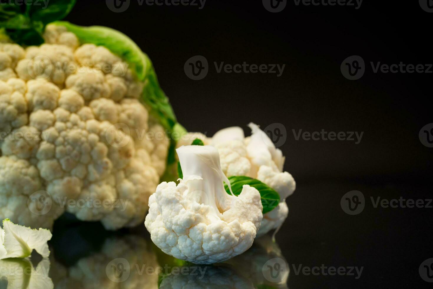 slices of raw small raw cauliflower on black background photo