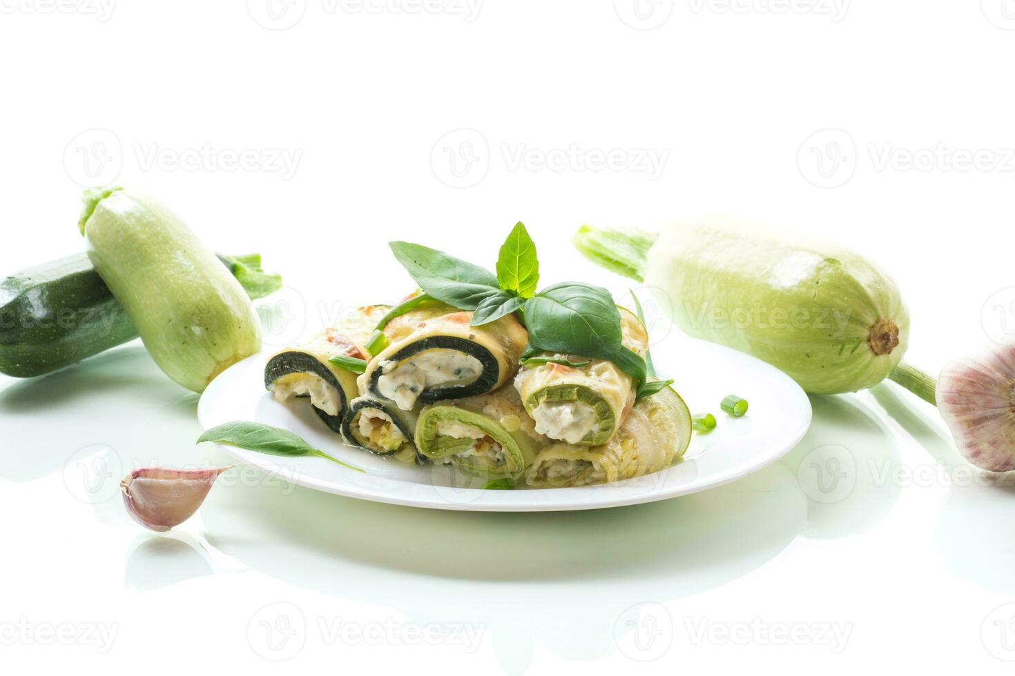 cooked zucchini rolls with cheese filling inside, in a plate photo