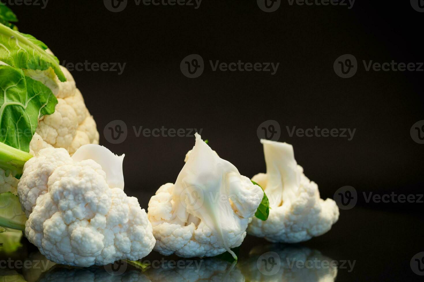 slices of raw small raw cauliflower on black background photo
