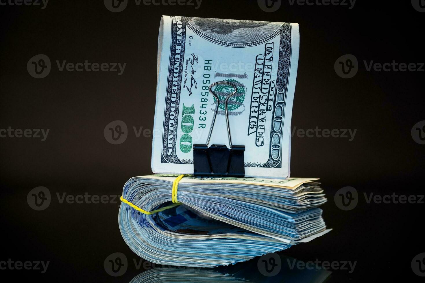 stack of dollar bills collected in an elastic band and a stationery clip photo