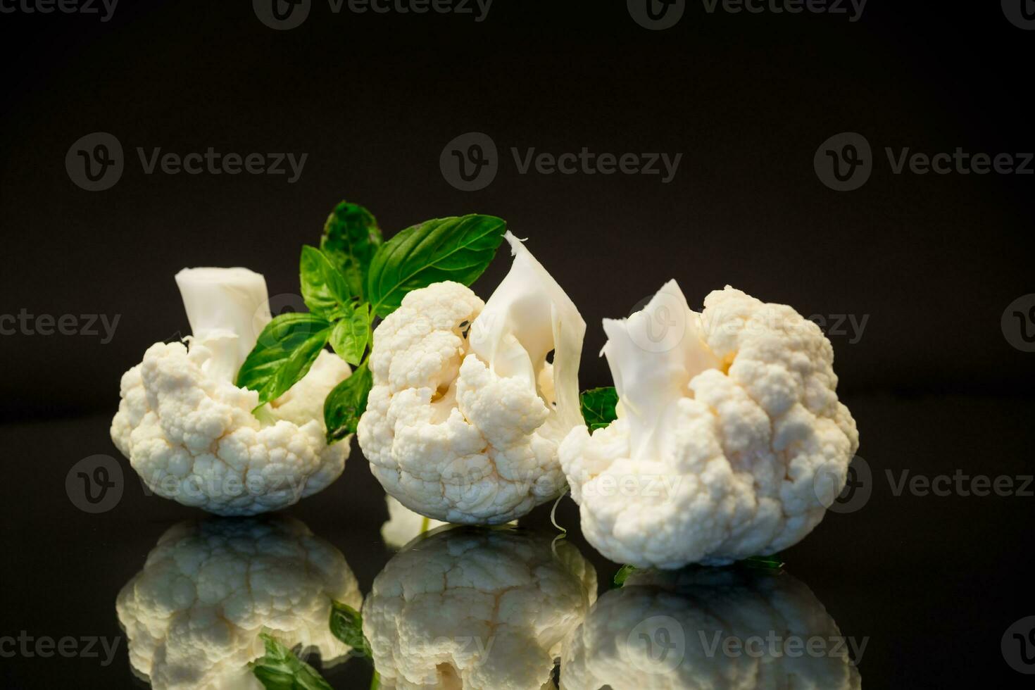 slices of raw small raw cauliflower on black background photo