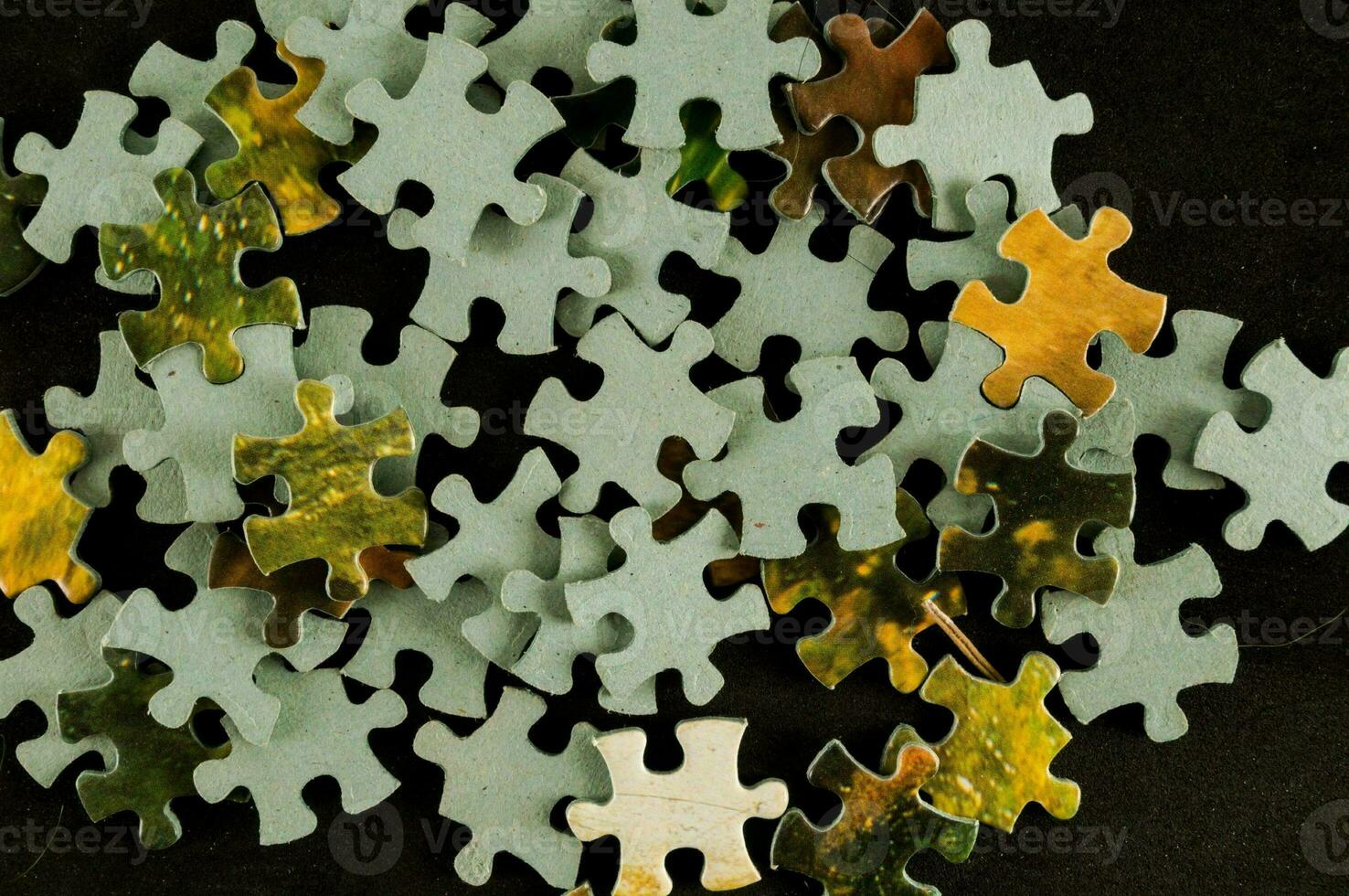 a pile of puzzle pieces on a black surface photo