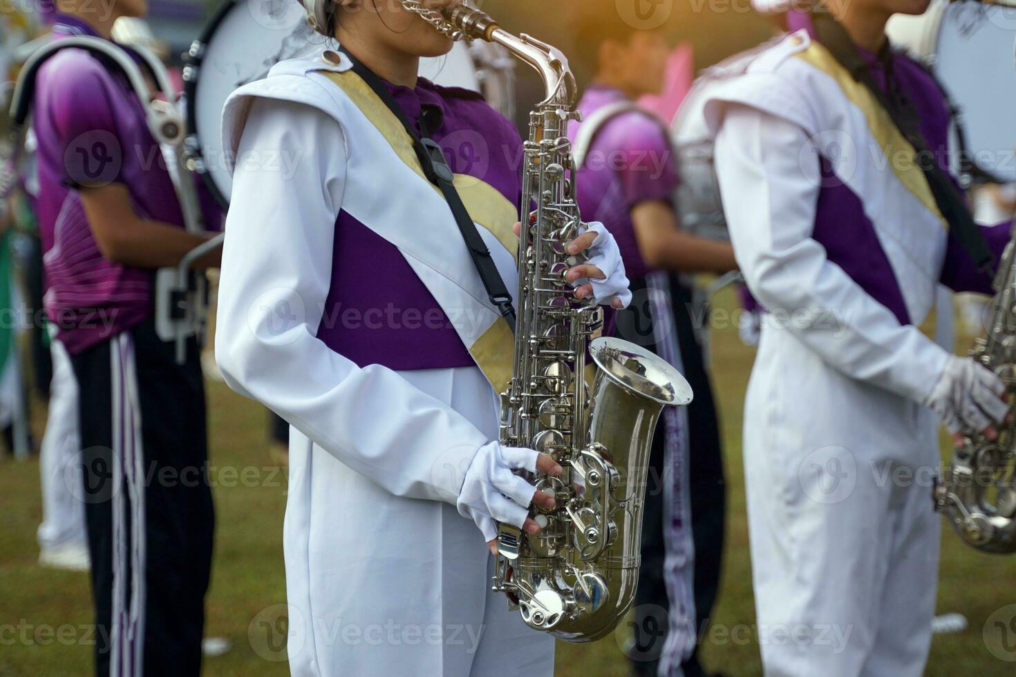 Orchestra students play saxophones in a parade at the school's athletics event. Soft and selective focus. photo