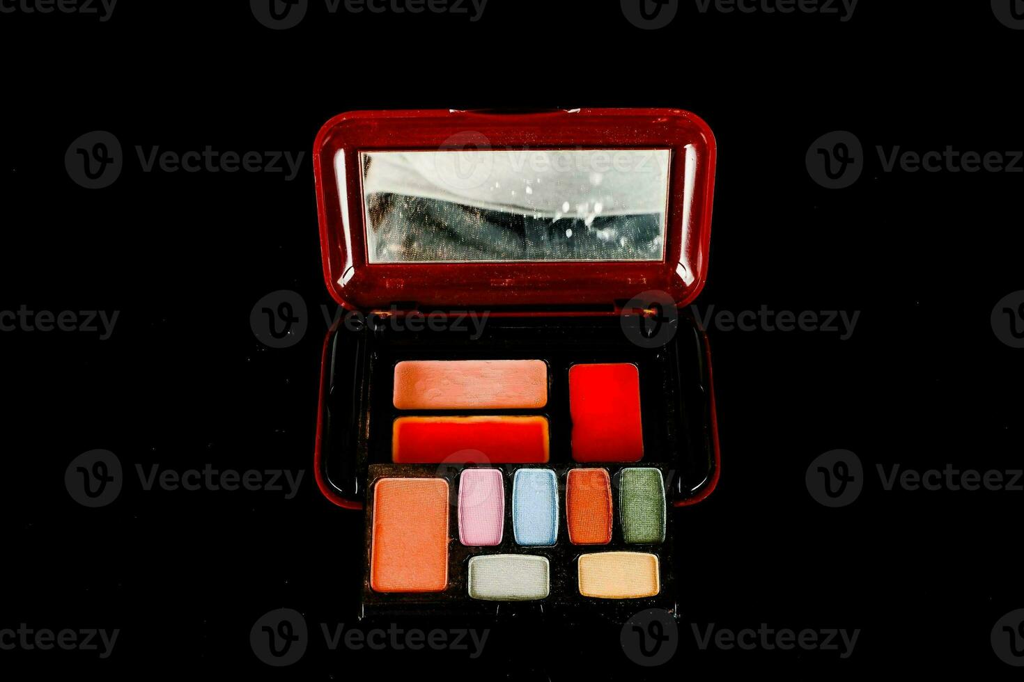 un rojo compacto con un espejo y varios maquillaje productos foto