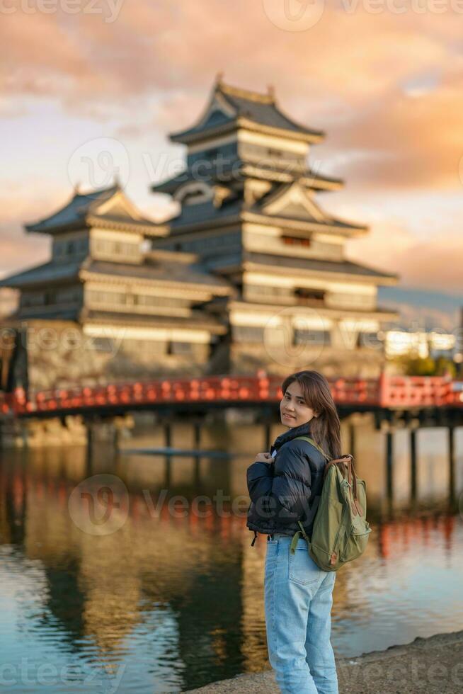 mujer turista visitando en matsumoto, contento viajero Turismo matsumoto castillo o cuervo castillo. punto de referencia y popular para turistas atracción en matsumoto, nagano, Japón. viaje y vacaciones concepto foto