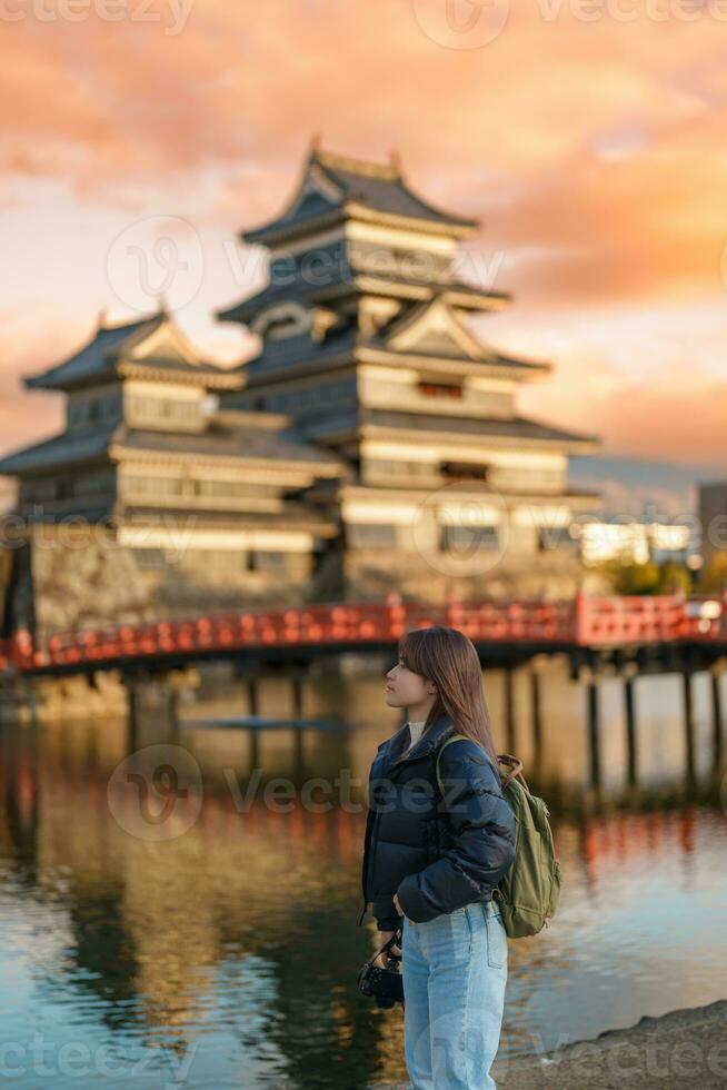 mujer turista visitando en matsumoto, contento viajero Turismo matsumoto castillo o cuervo castillo. punto de referencia y popular para turistas atracción en matsumoto, nagano, Japón. viaje y vacaciones concepto foto