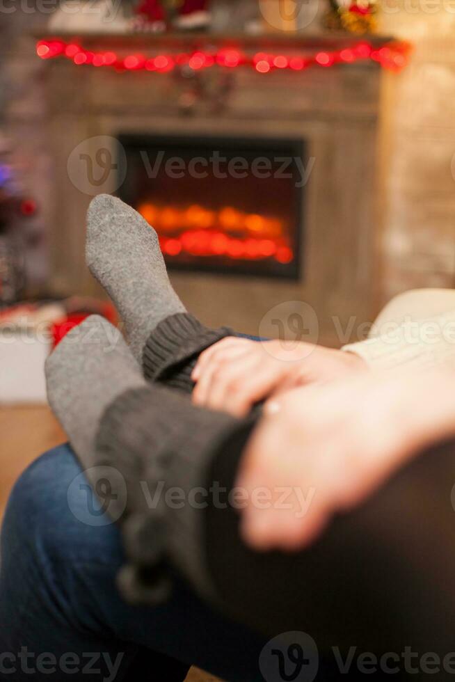 novio participación su manos en su Novia pies celebrando Navidad en vivo habitación. foto