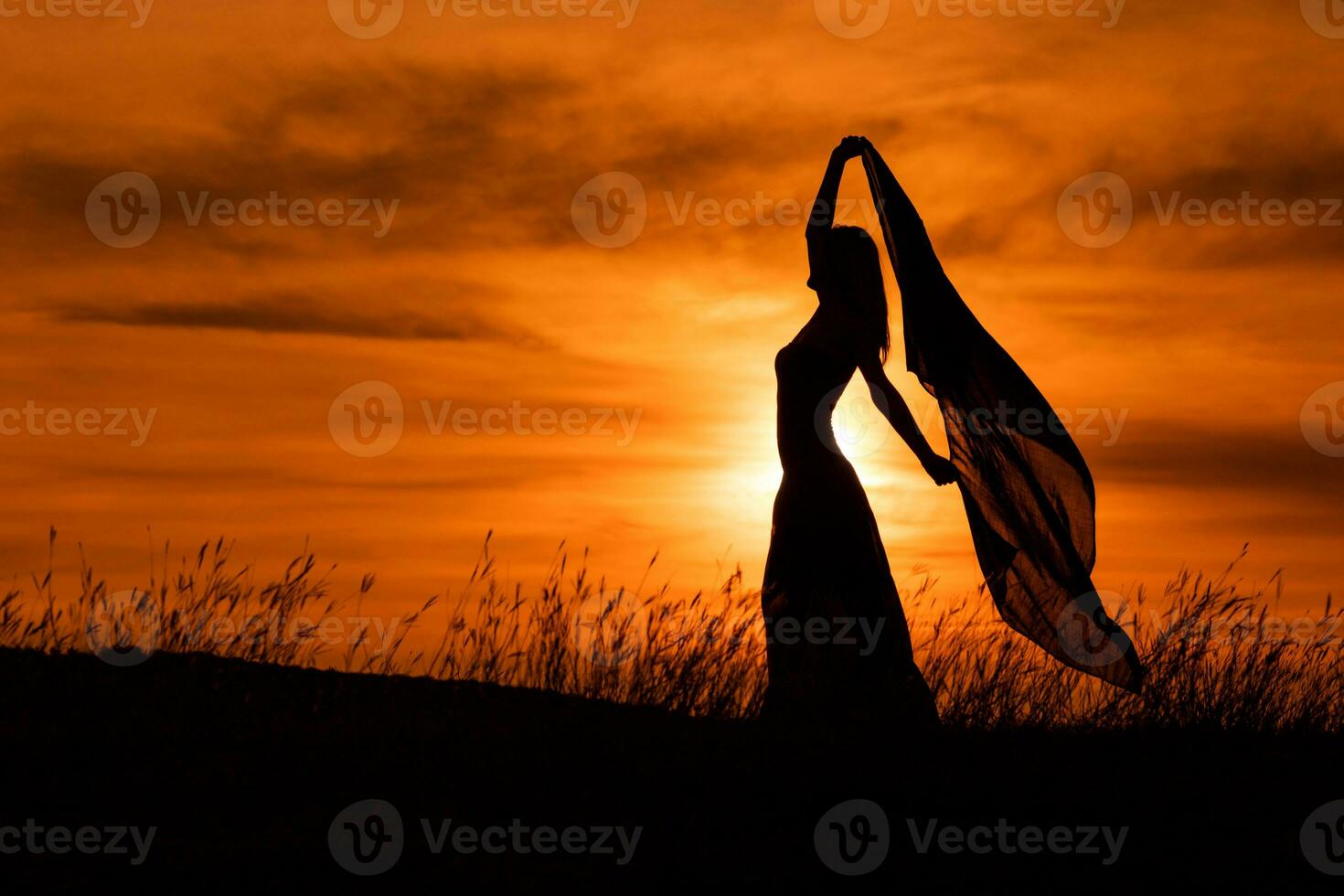 Happy woman dancing and holding scarf while enjoys spending time at sunset. photo