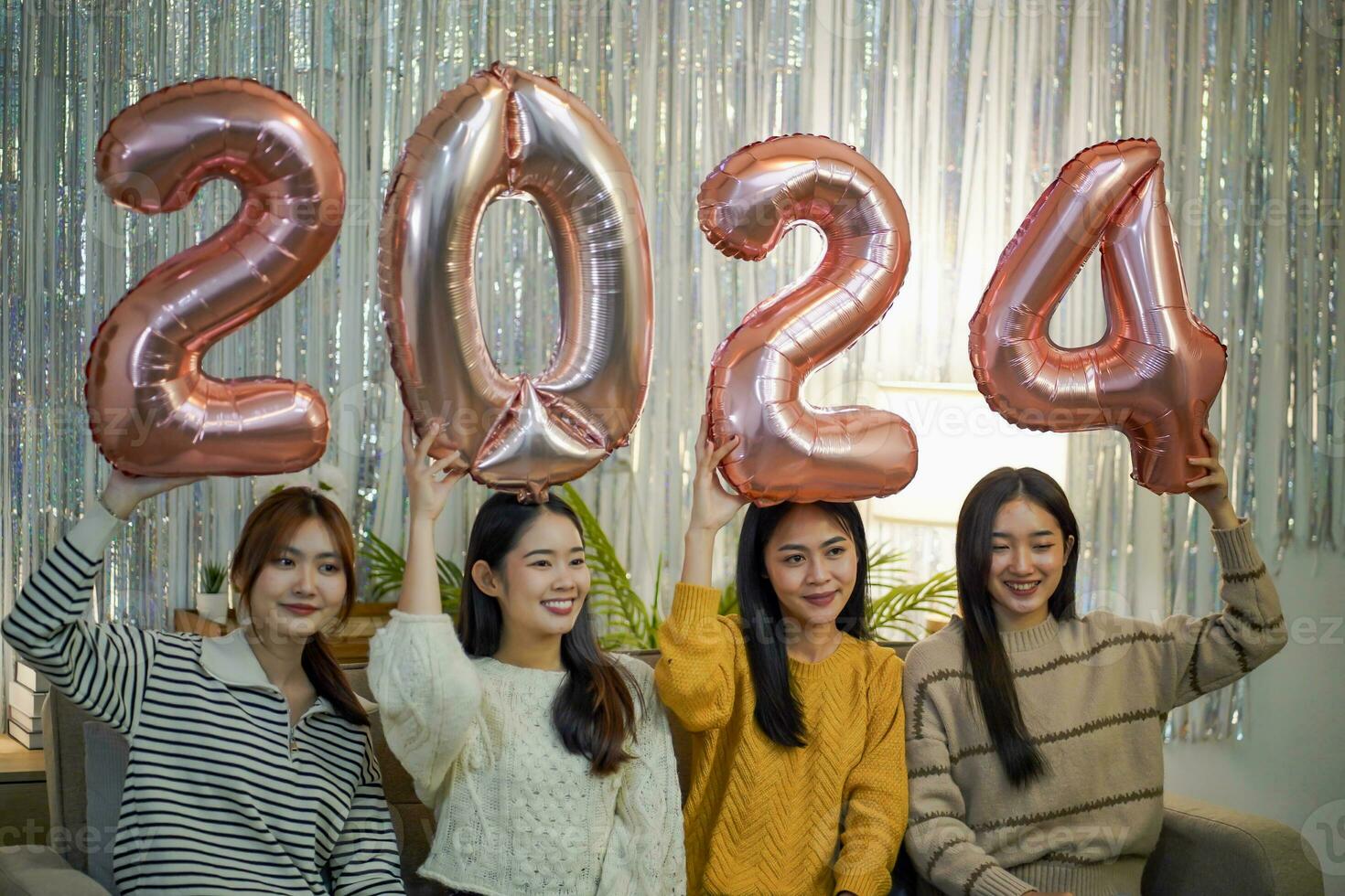 Happy Cheerful friends enjoying home holiday party. Asian Friends celebrating Christmas or New Year eve party numbers 2024. photo