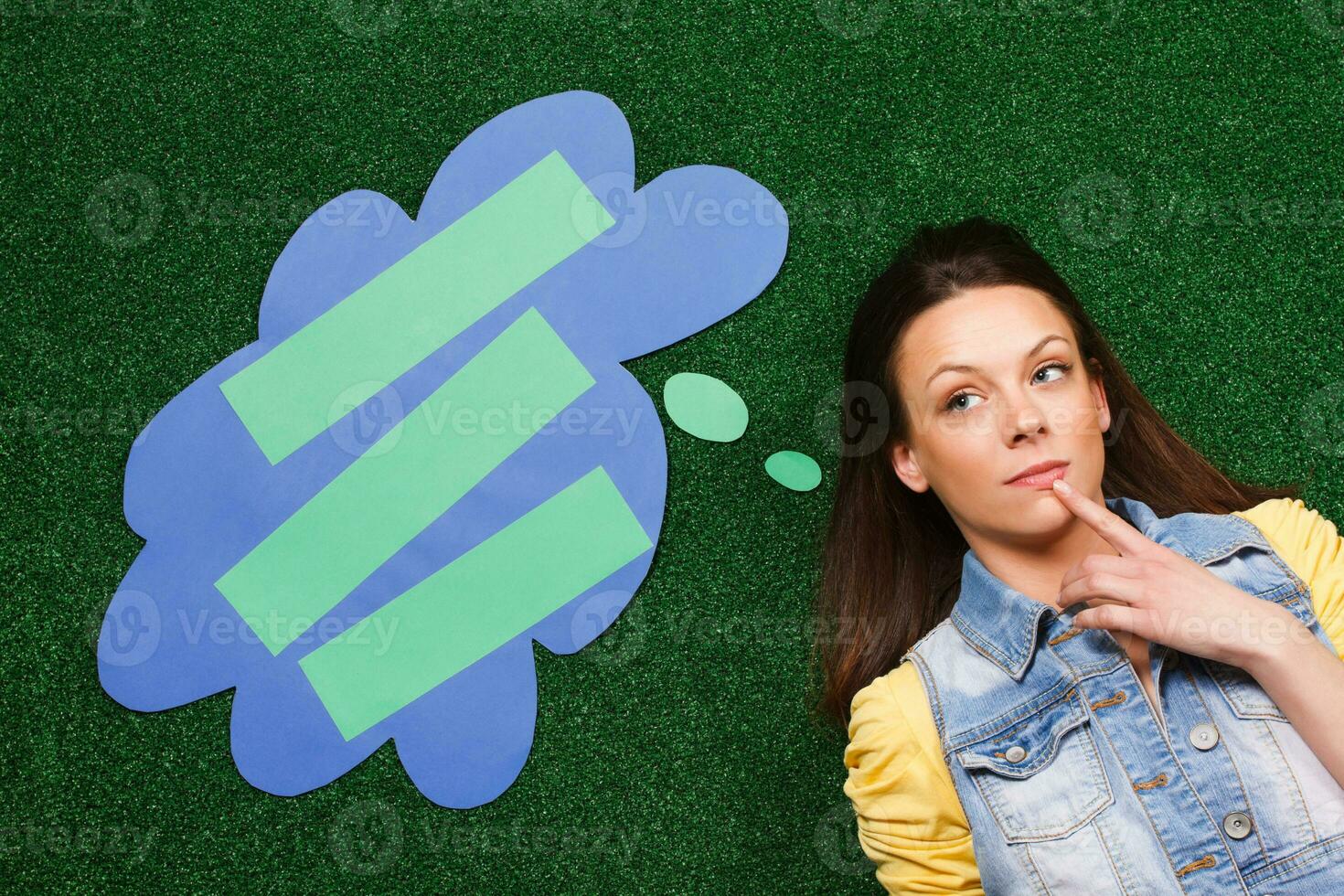 Woman thinking with a thought bubble lying on the grass photo