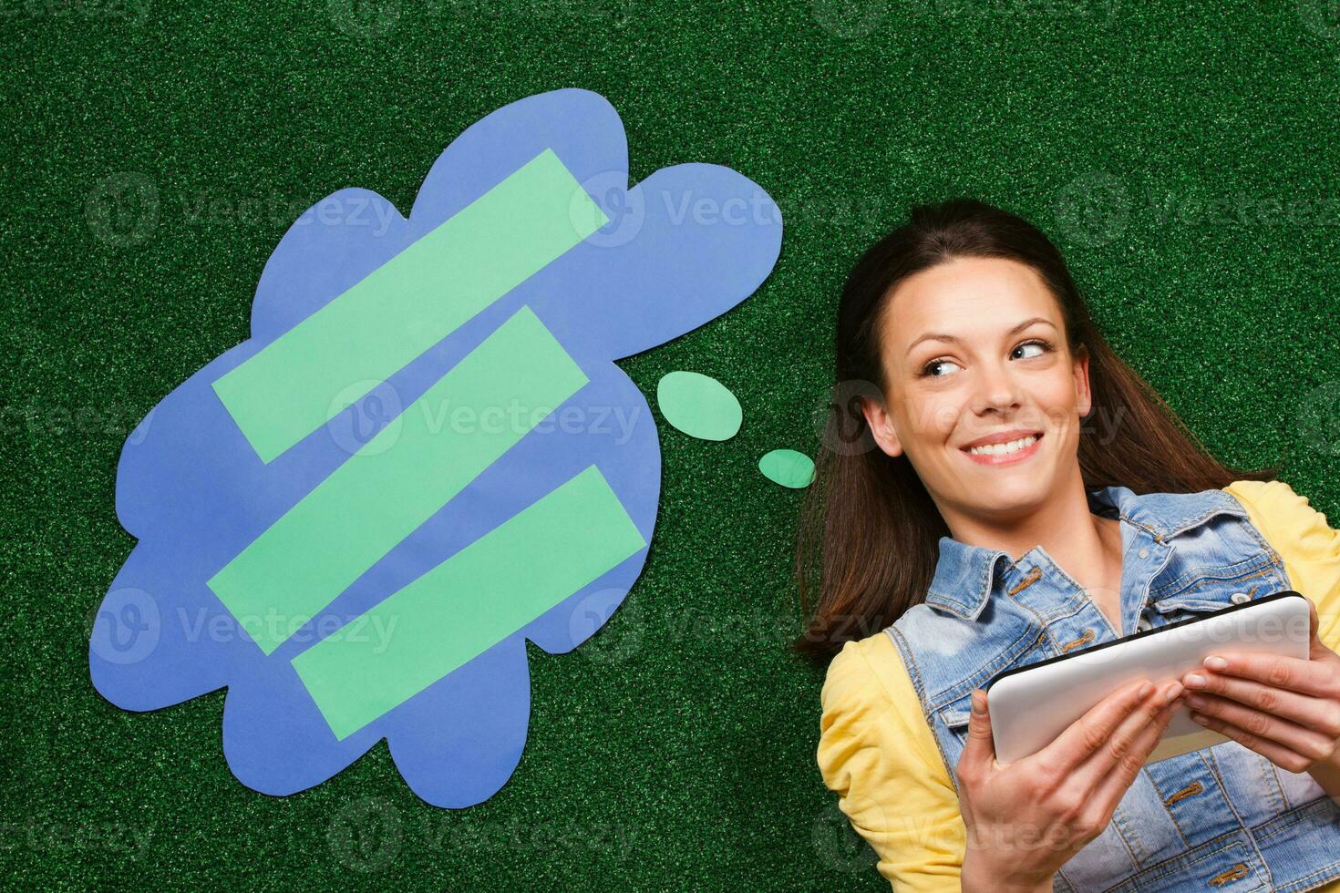 Woman thinking with thought bubble while using digital tablet photo