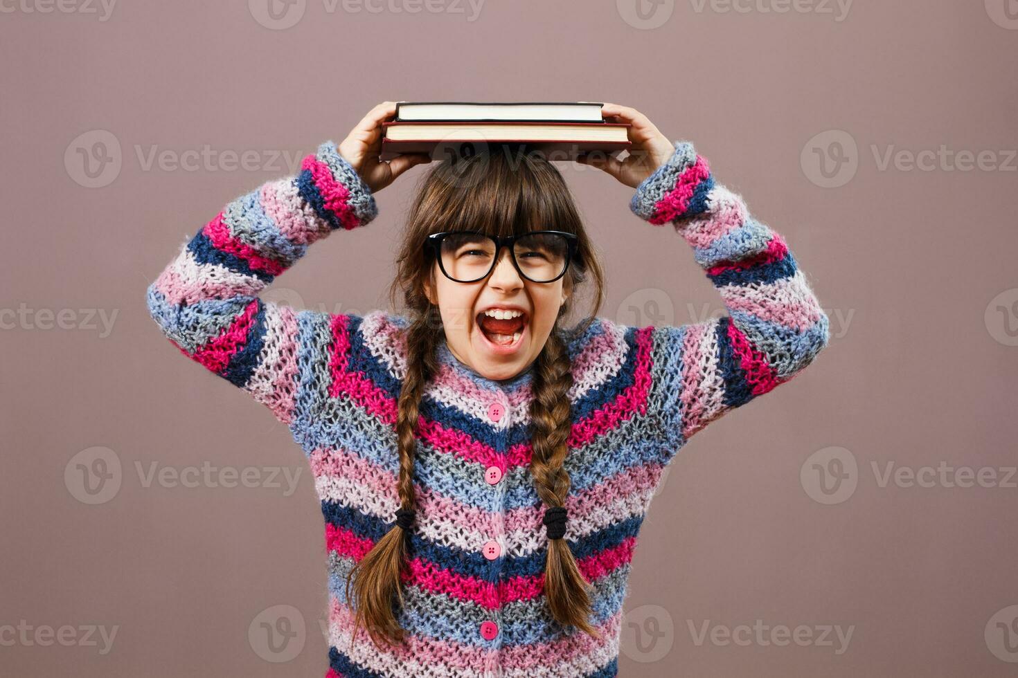 Angry little nerd girl screaming and holding books photo