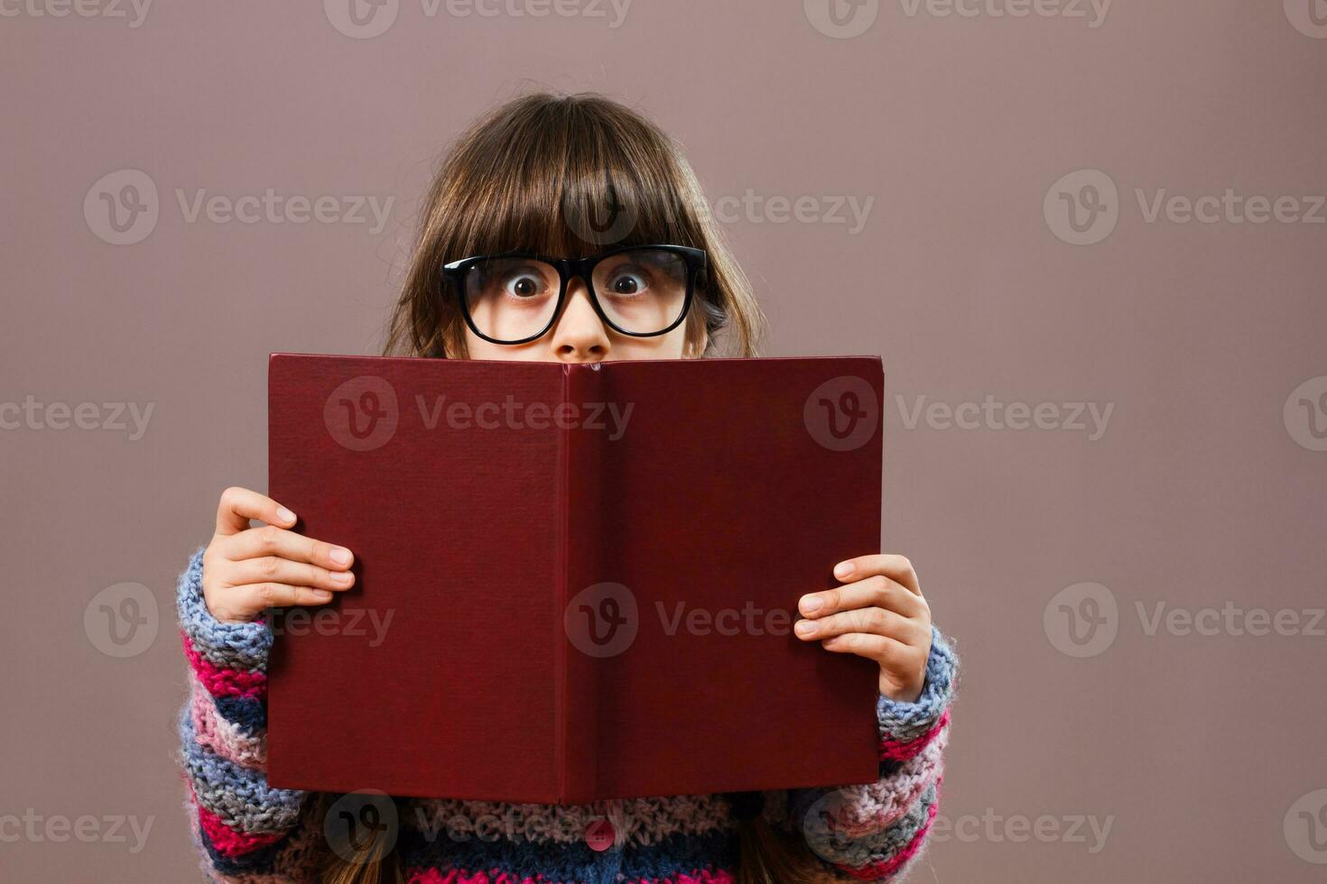 Little nerdy girl hiding behind a book photo