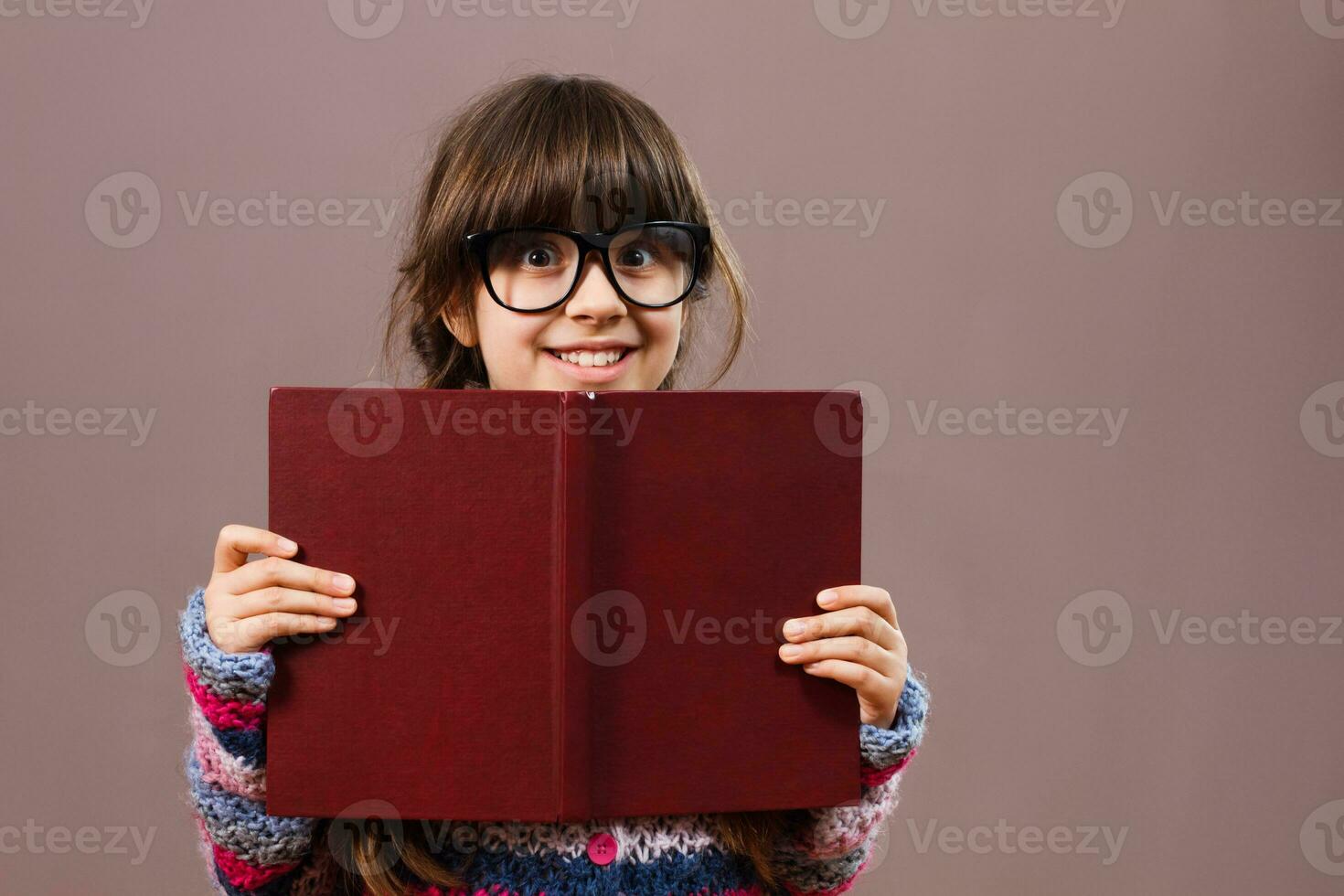 Little nerdy girl hiding behind a book photo