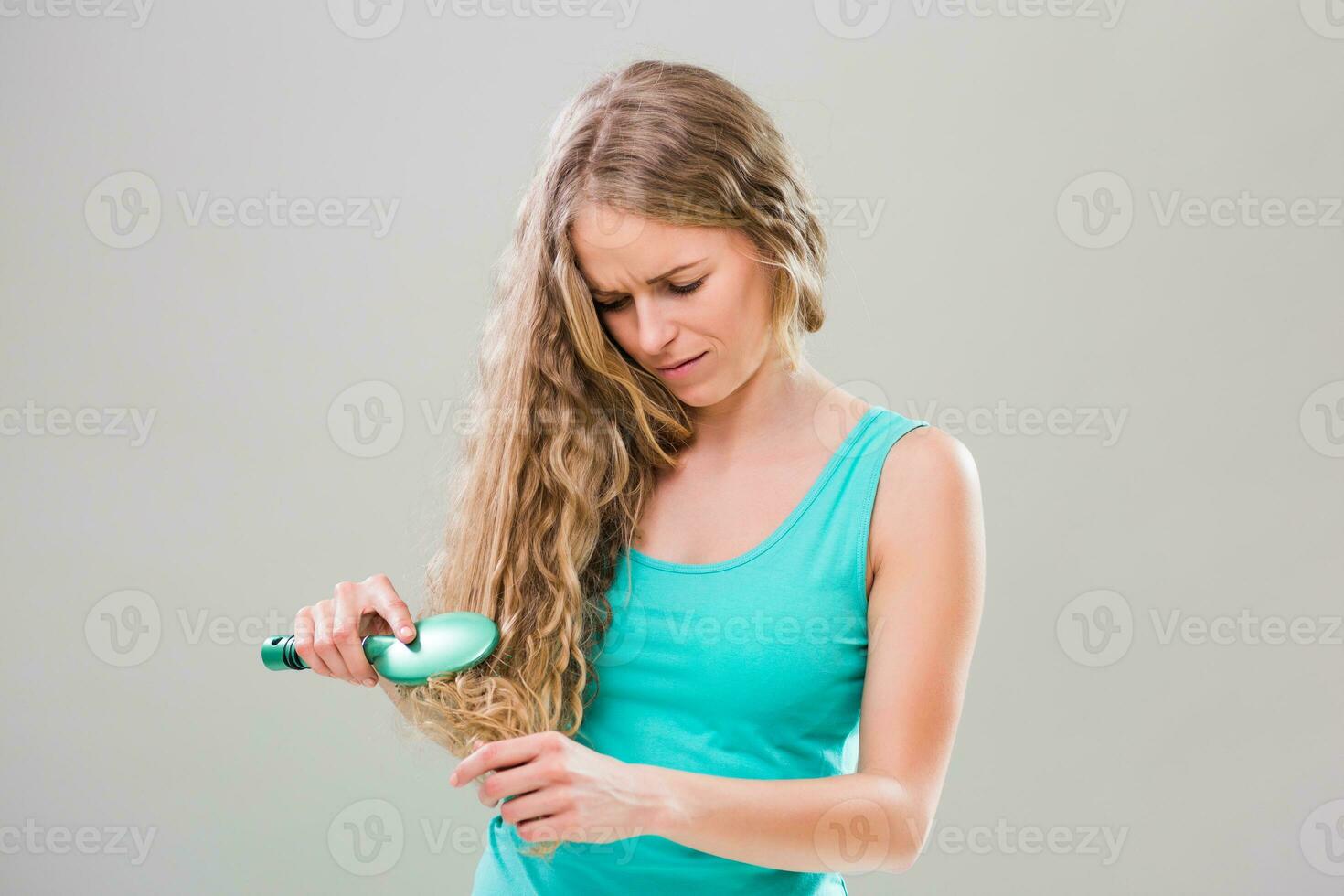 Young woman is tired of brushing her long her every day. photo