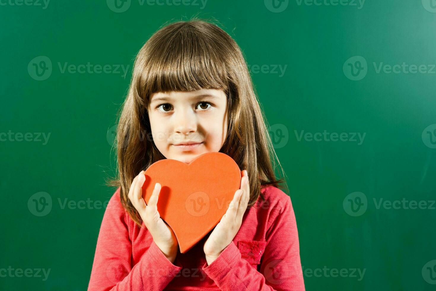 Little girl holding heart shape photo