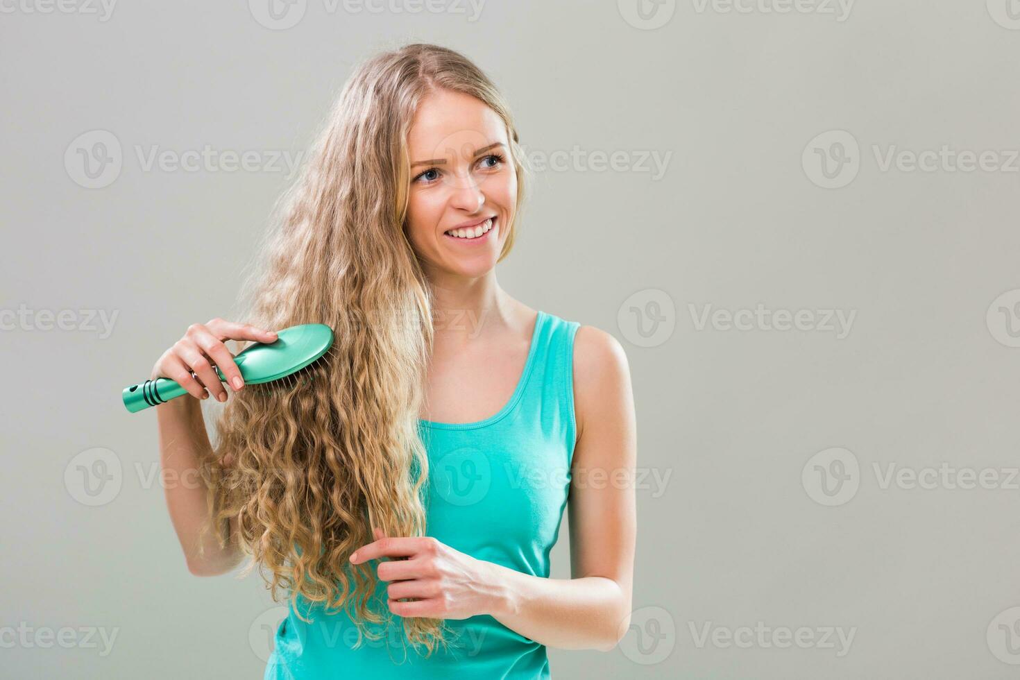 joven mujer cepillado su maravilloso largo rubia cabello. foto