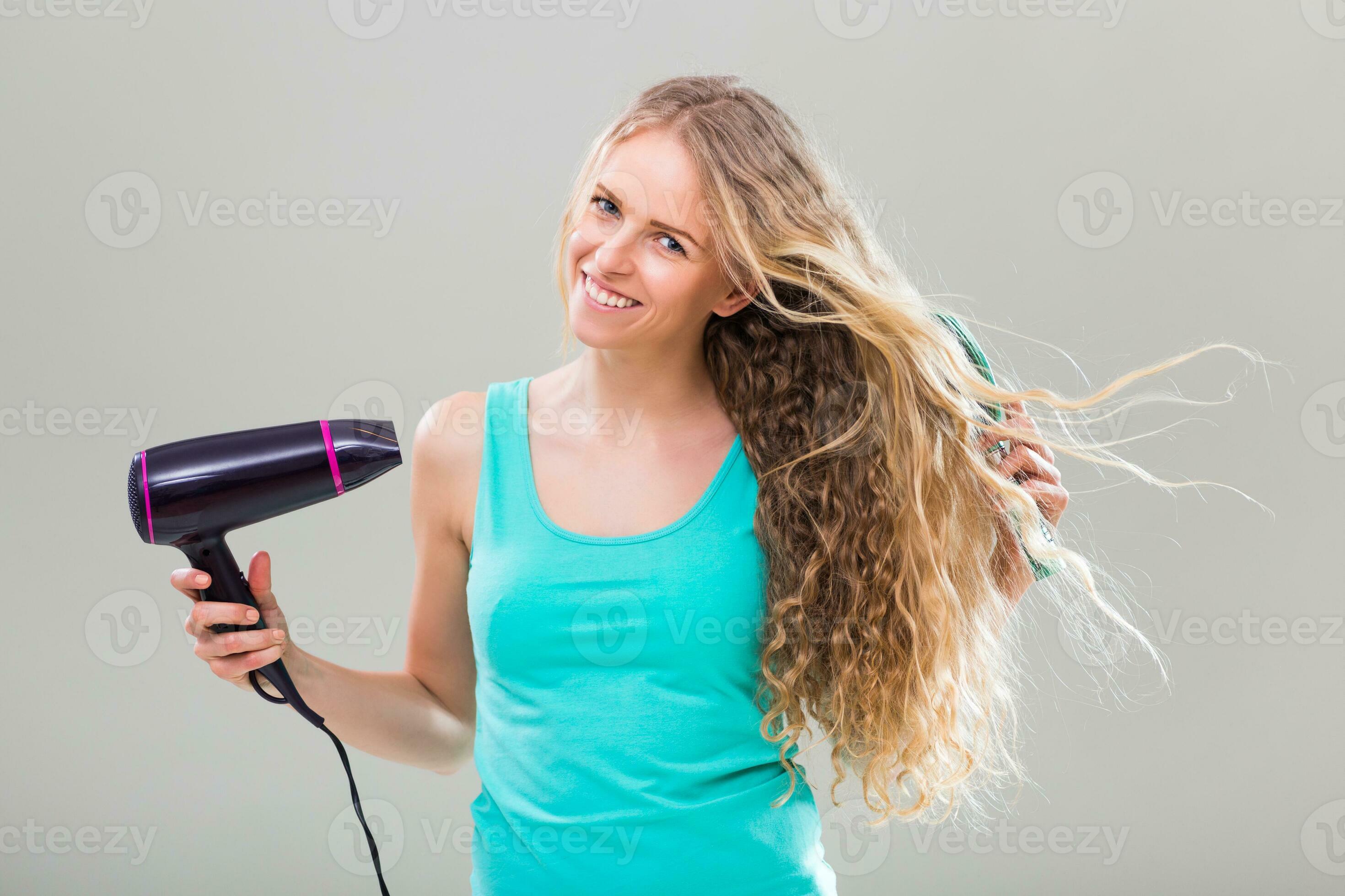 Joven hermosa mujer con pelo rizado usando secador de pelo sobre