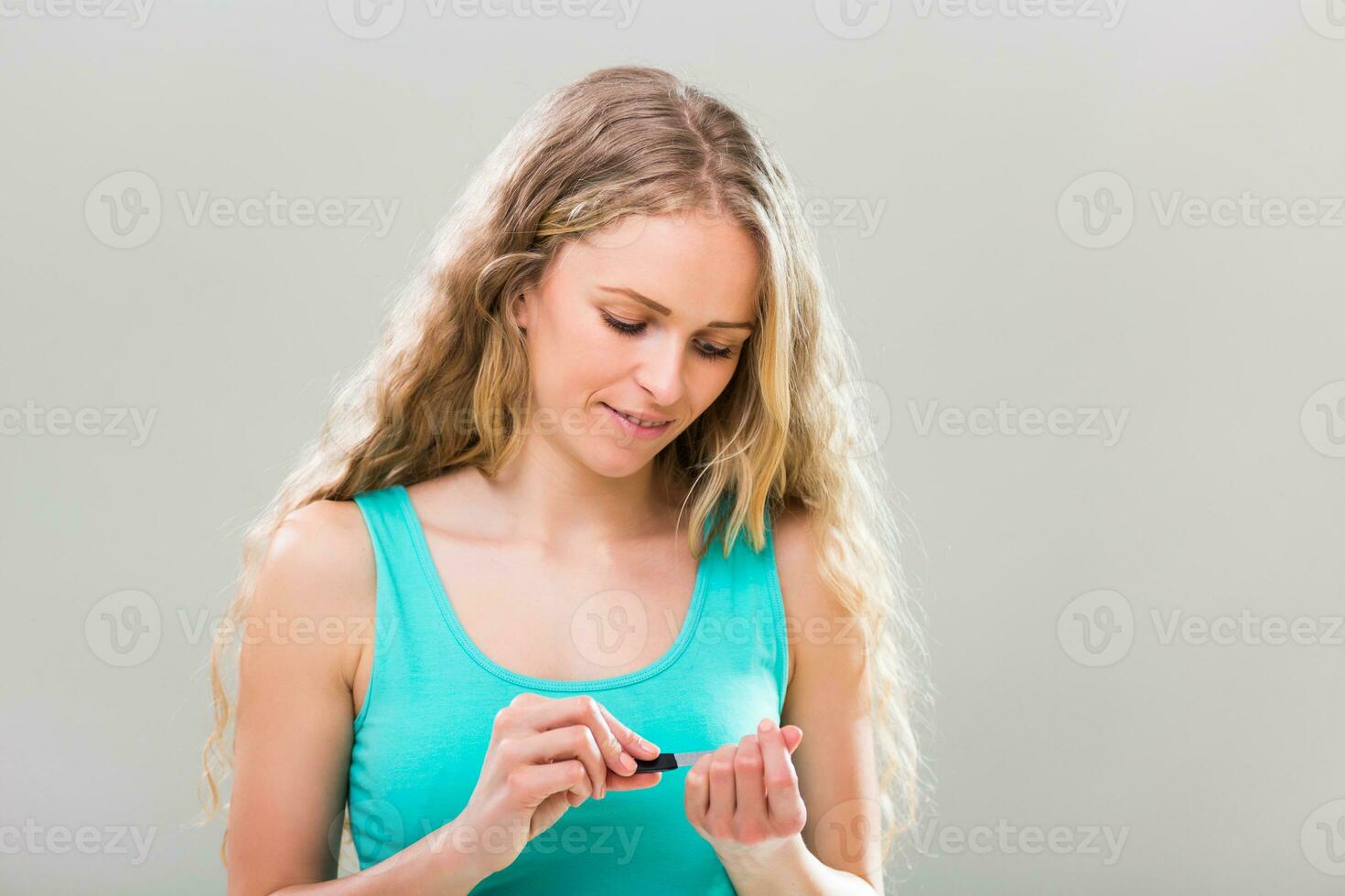 Beautiful woman using nail file on gray background. photo