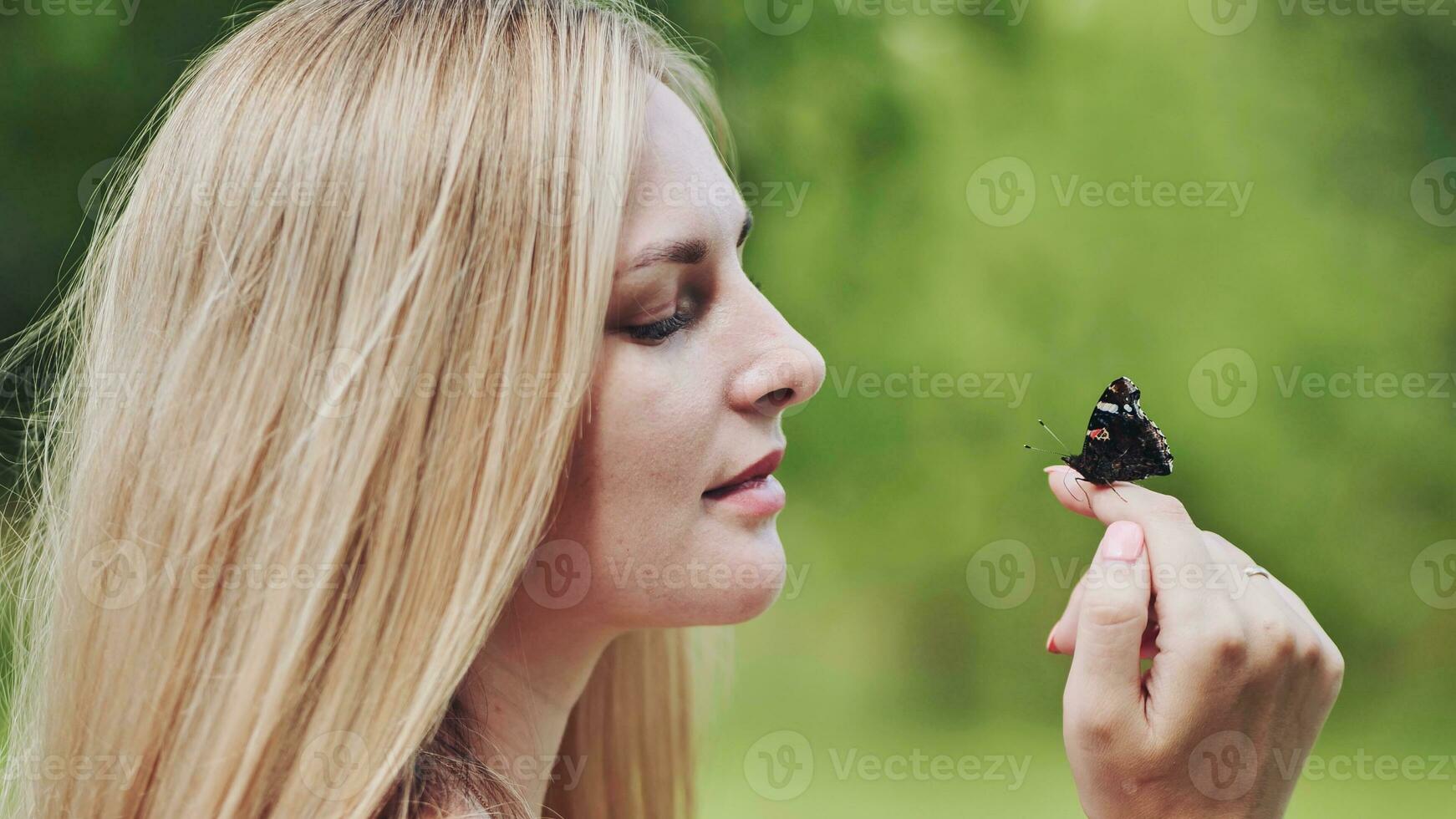 The girl gently enjoys the butterfly that flew to her. photo