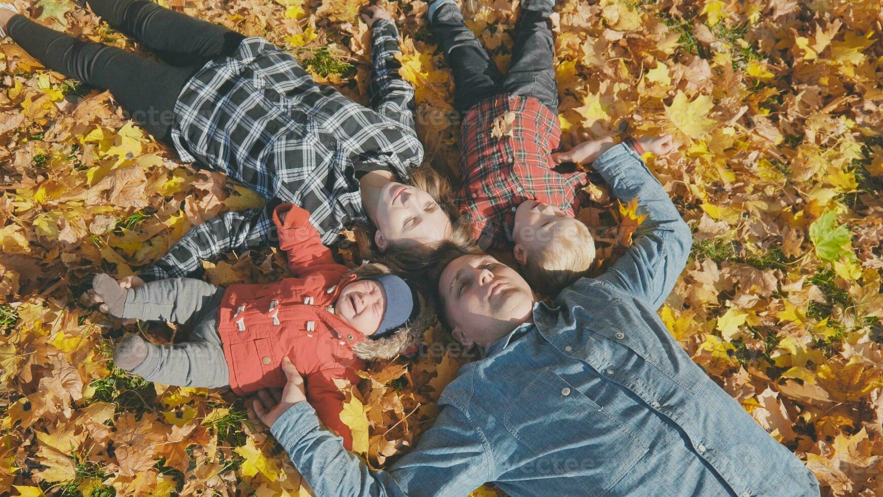 The happy family lies on their backs in the autumn leaves. photo