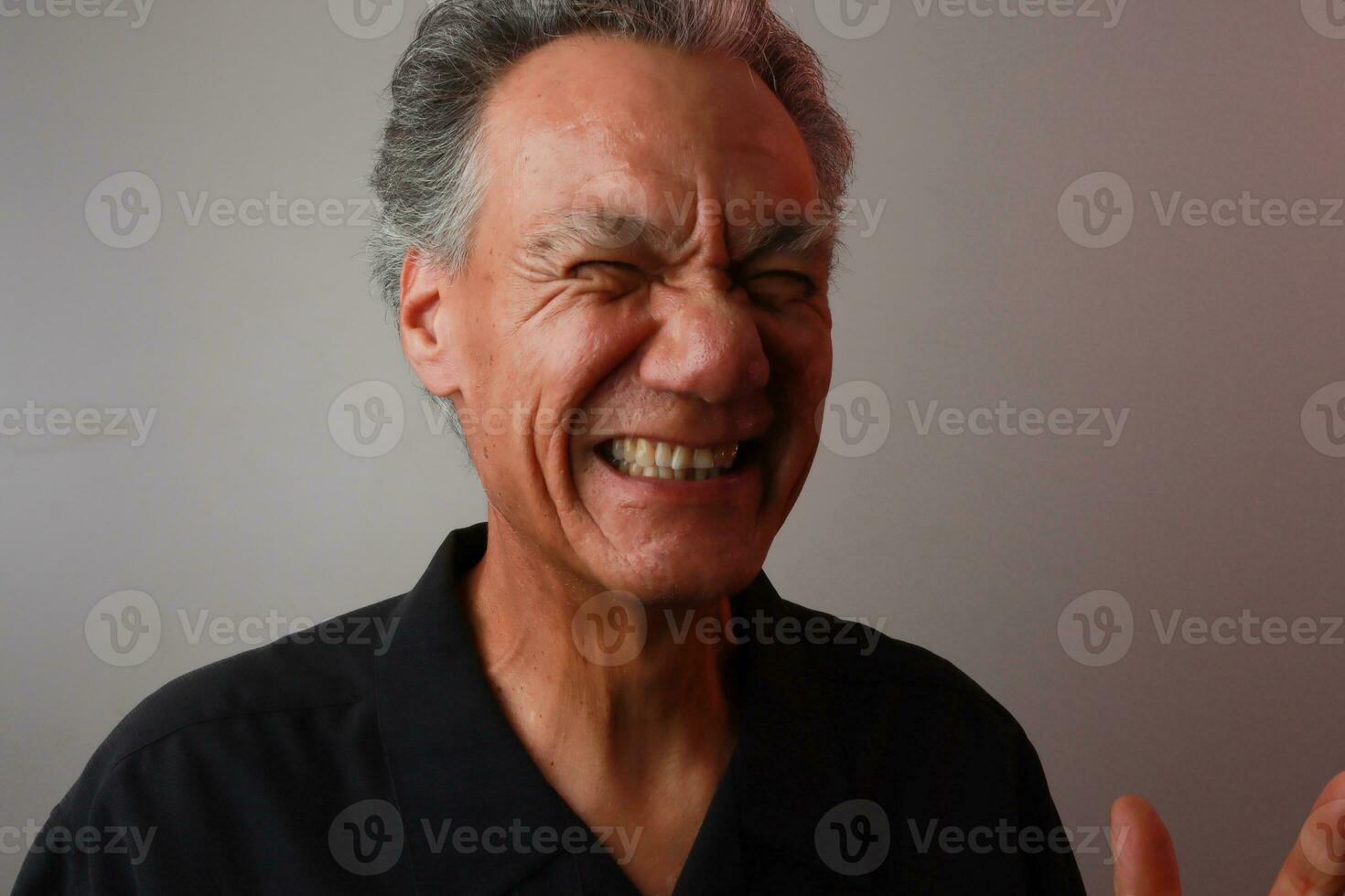 Older Mature Man against a Gray background breaking out in laughter photo