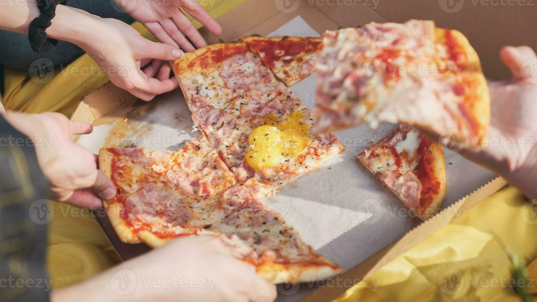 Young students' hands reach for the pizza. photo