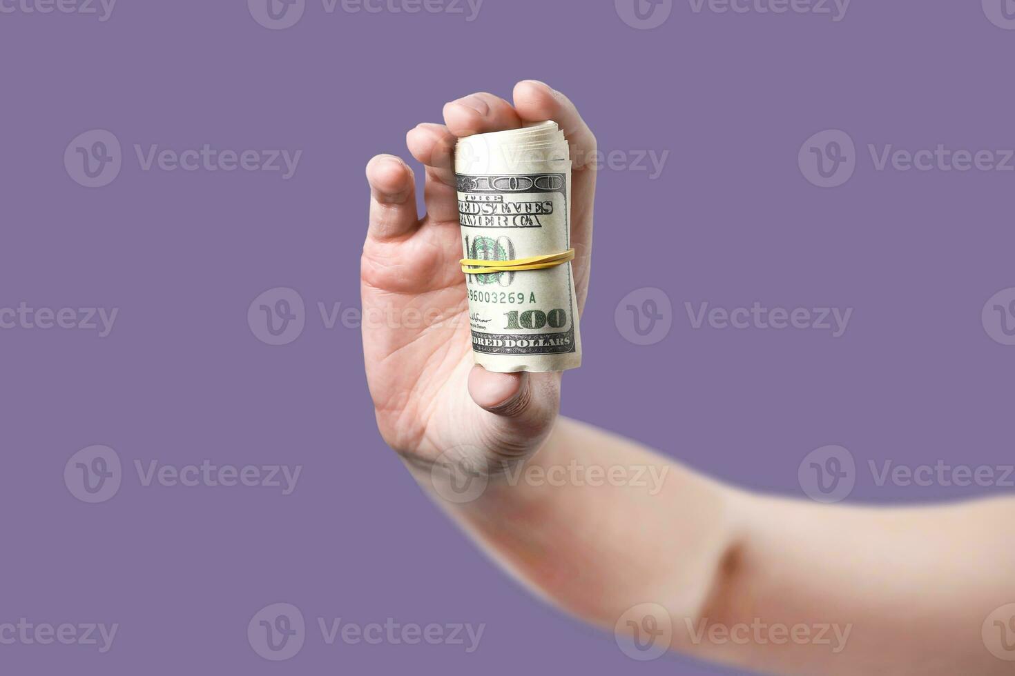 Woman's hand shows rolled up money violet background photo