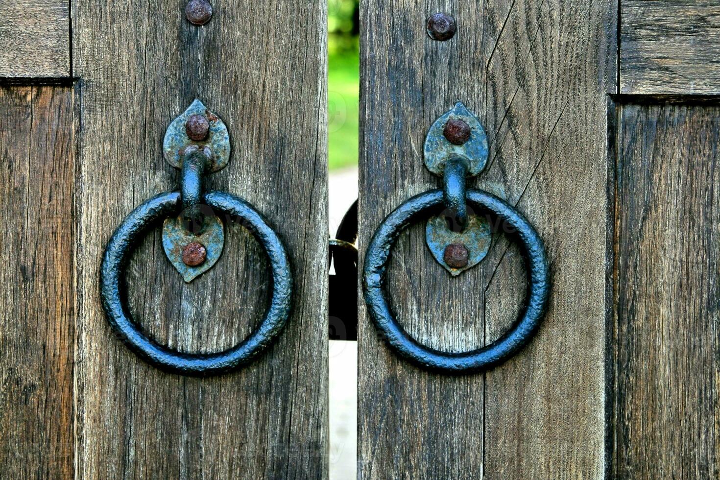 Ancient wooden gate with door knocker rings photo