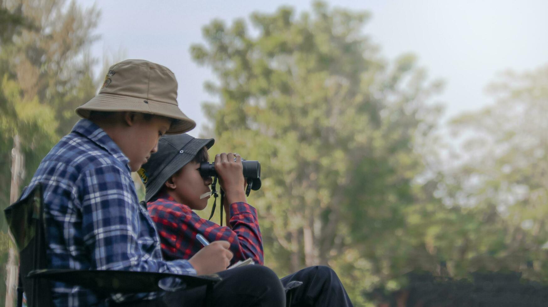 Young Asian boys are using a measure tape to measure a tree in a local park, soft and selective focus photo