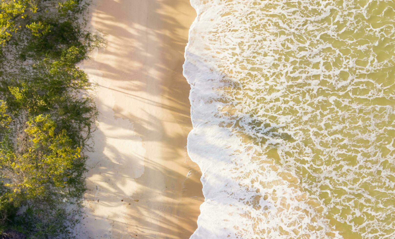 Aerial top view of sandy beach with stunning waves. photo
