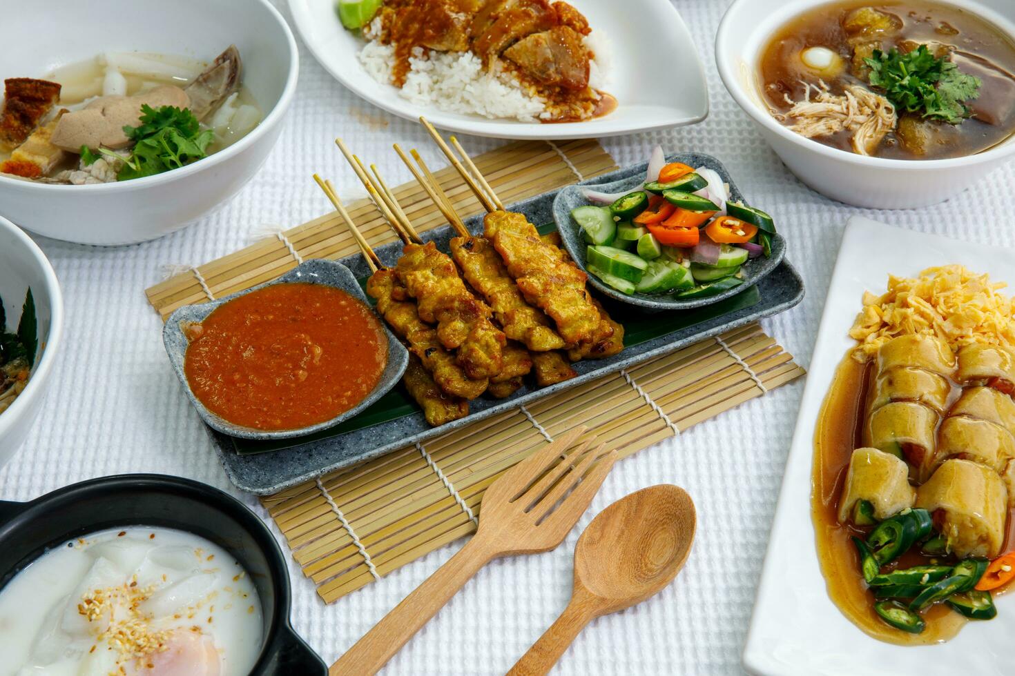 Pork Satay on plate. Grilled pork served with peanut dipping sauce,toasted bread and sweet sour sauce decorated with cucumber,onion and chili. One of the best Thai street food. photo