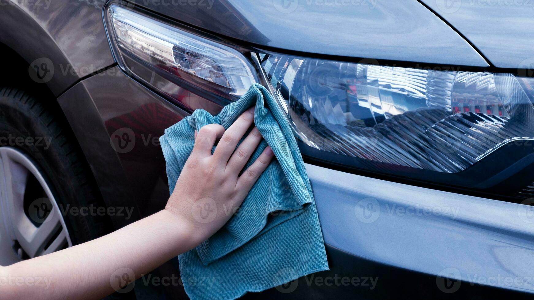 Wipe car with led headlight for customers, Woman cleaning car with microfiber cloth car detailing and valeting concepts. photo