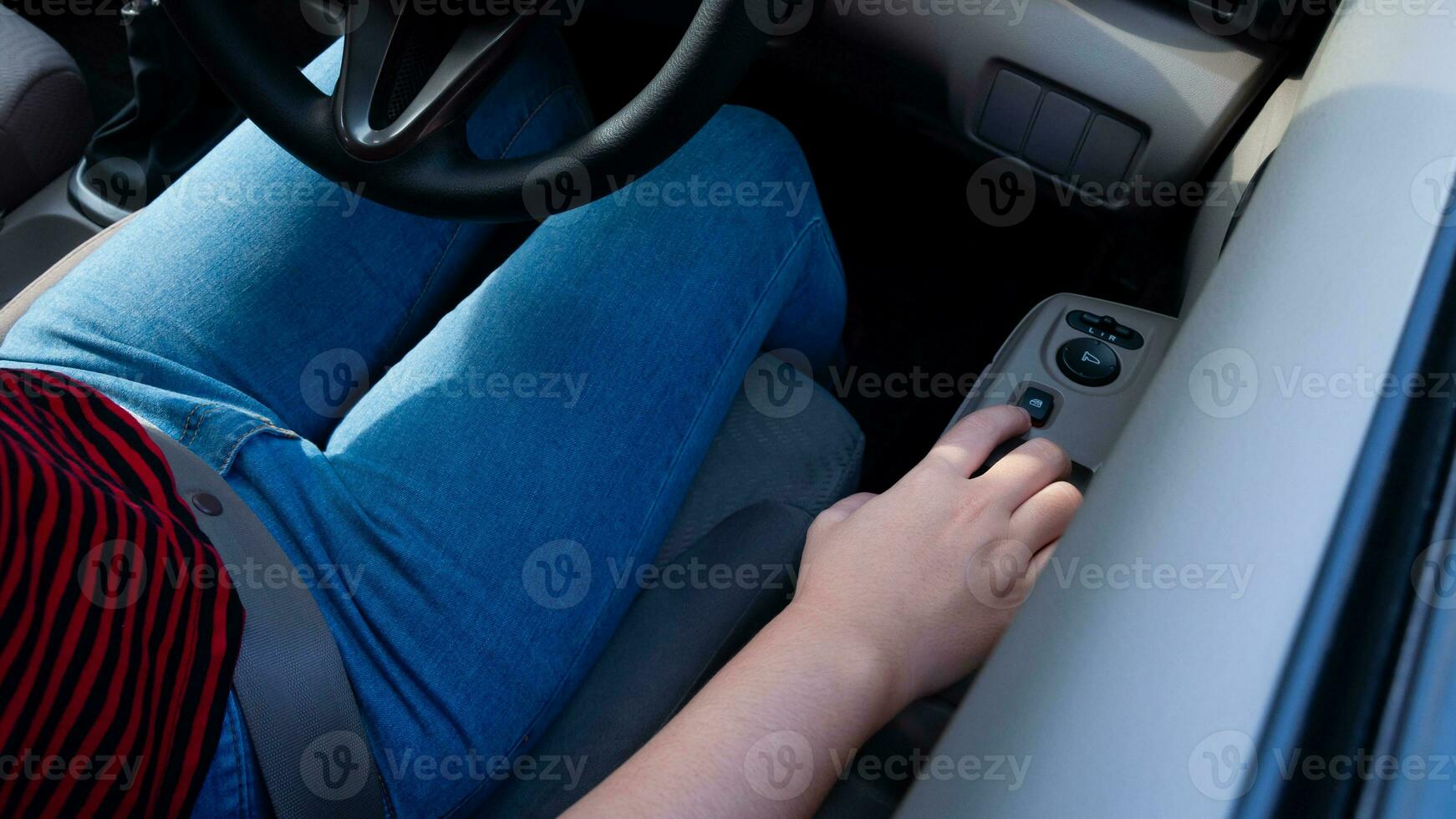 Hand pressing a car window lock button. driver is pressing buttons of window switches with remote control inside modern car, opening and lowering glass. photo