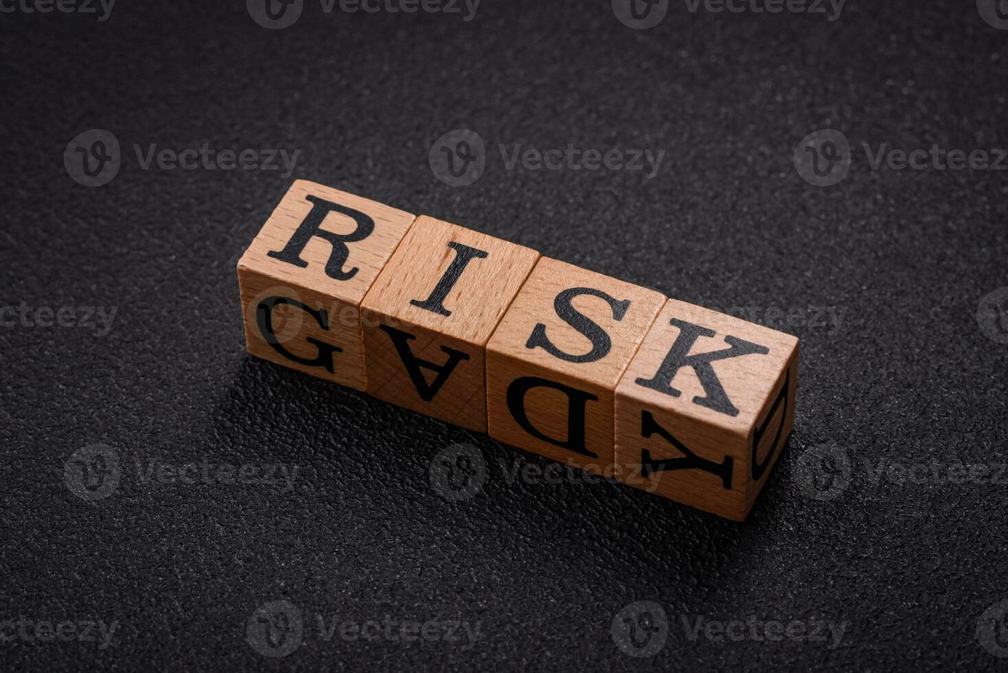 The inscription risk with wooden cubes on a dark concrete background photo