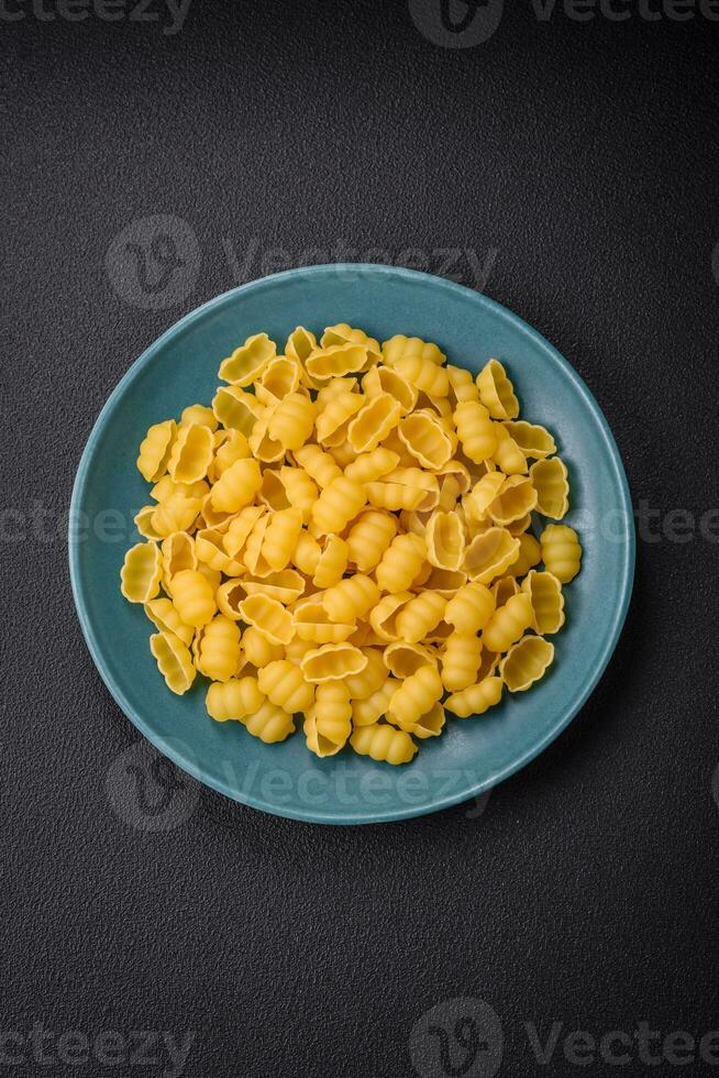 Raw durum wheat gnocchi pasta with salt and spices in a ceramic plate photo