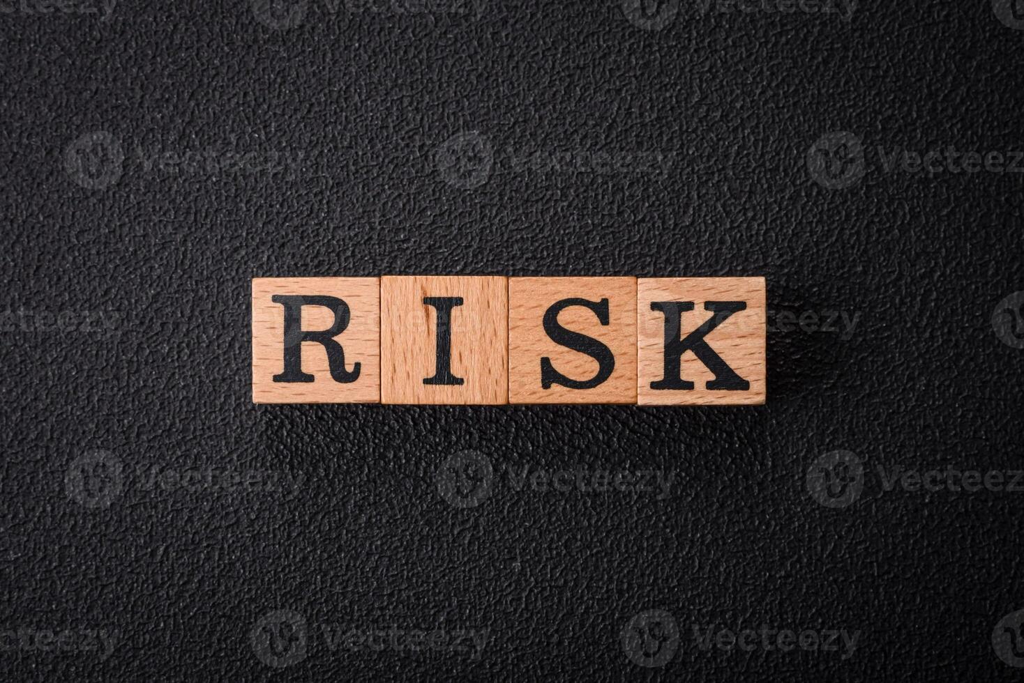 The inscription risk with wooden cubes on a dark concrete background photo