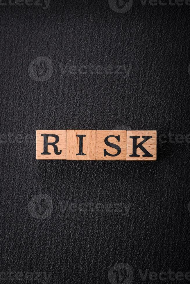 The inscription risk with wooden cubes on a dark concrete background photo