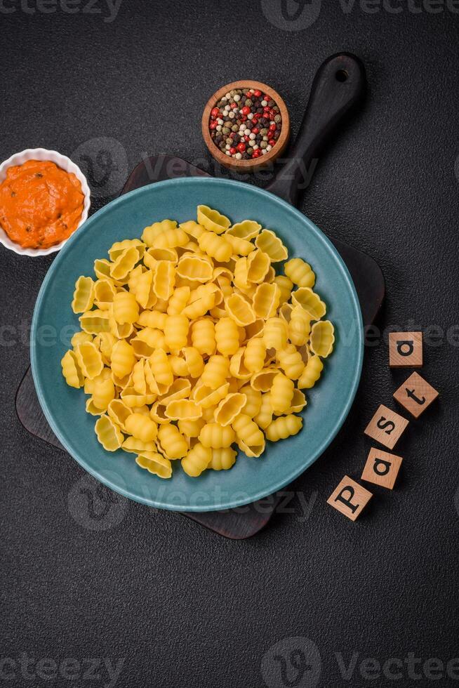 Raw durum wheat gnocchi pasta with salt and spices in a ceramic plate photo