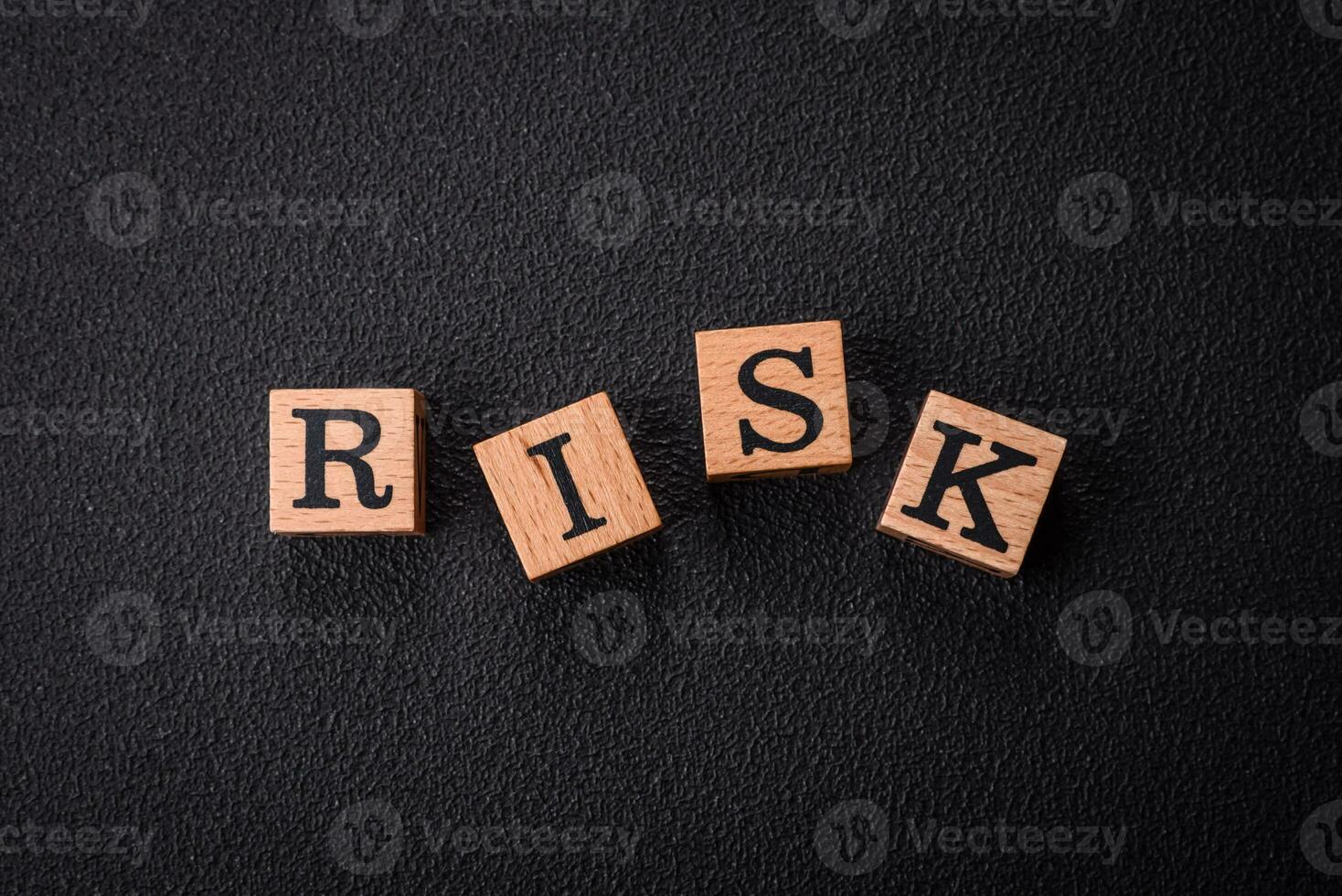 The inscription risk with wooden cubes on a dark concrete background photo