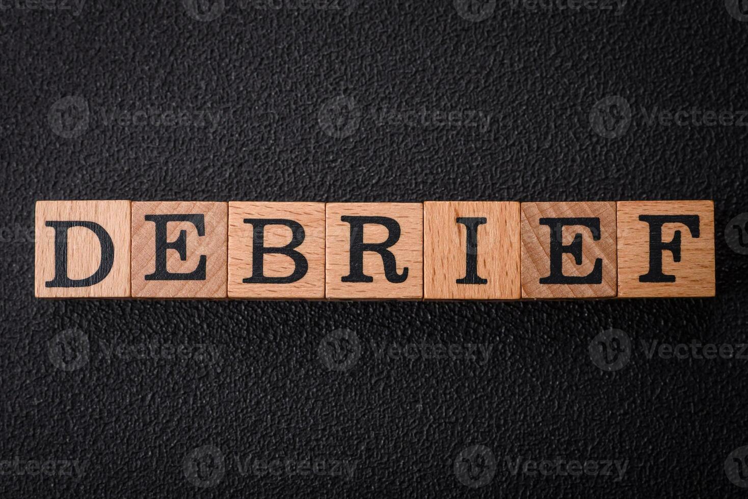 The inscription debrief in wooden cubes on a dark concrete background photo