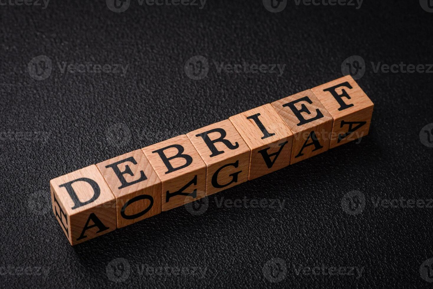 The inscription debrief in wooden cubes on a dark concrete background photo